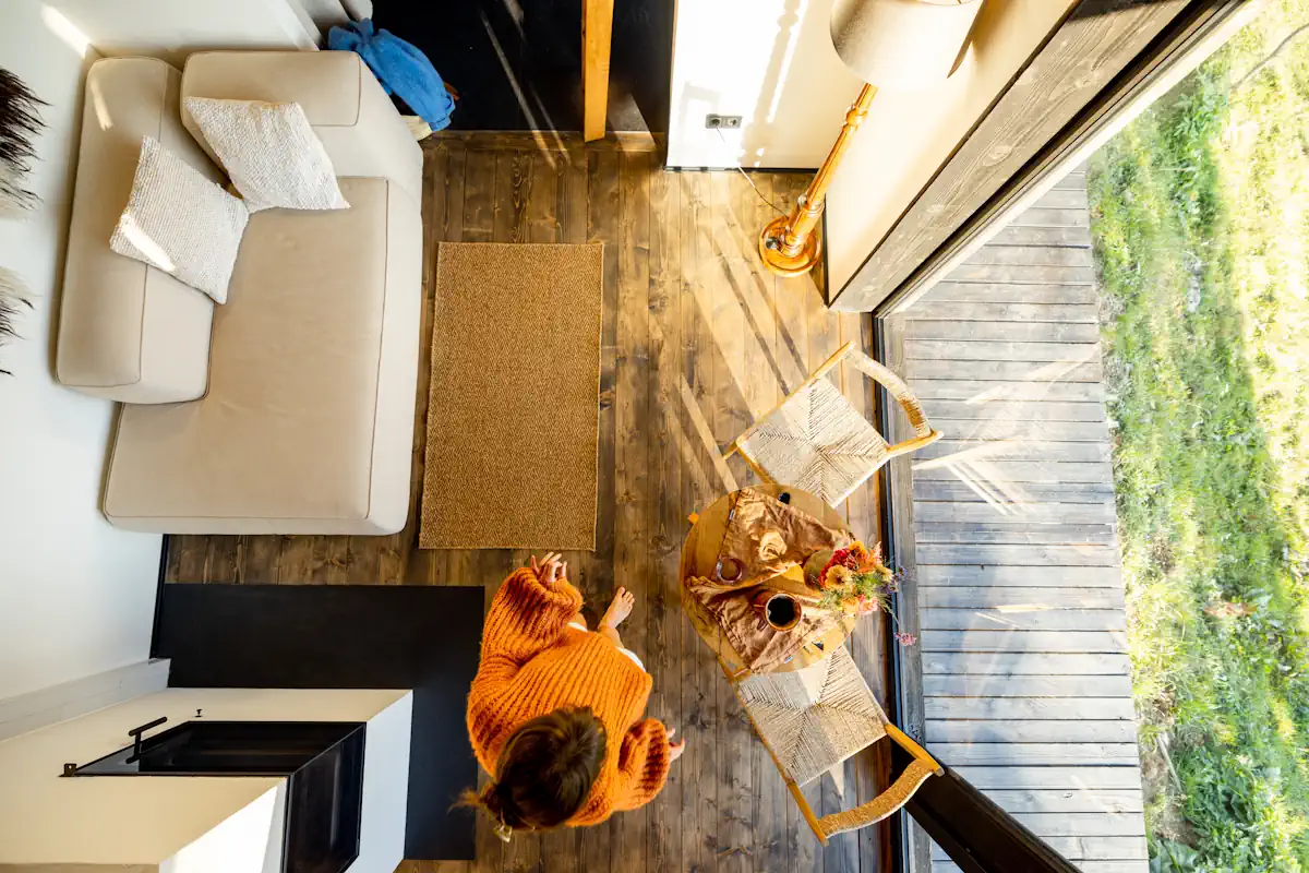 Une femme qui marche pieds nu dans une pièce avec un sol en bois avec un canapé et des éléments de déco