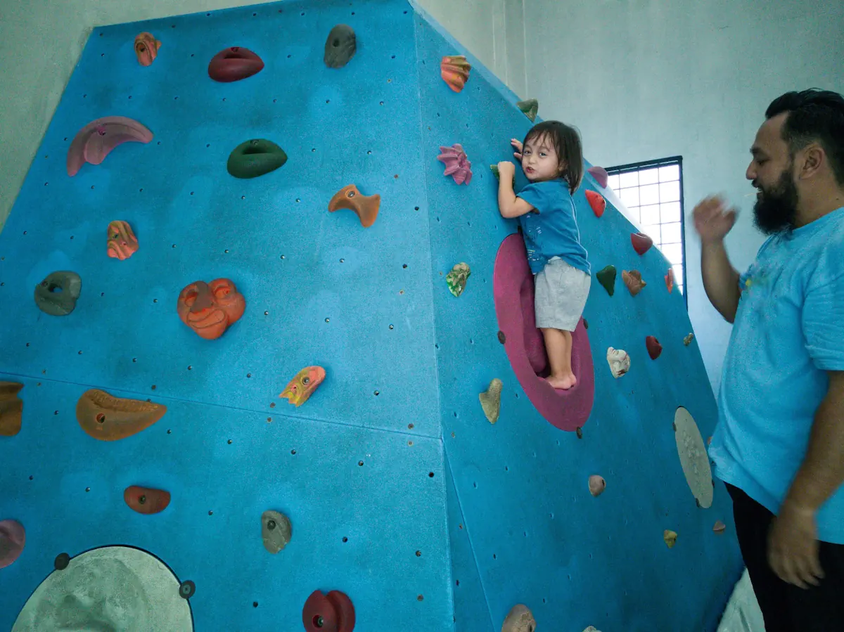 Une petite fille qui fait de l'escalade sous le regard d'un homme